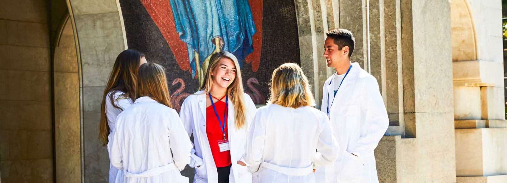 Students standing outside the entrance to a hospital chatting.