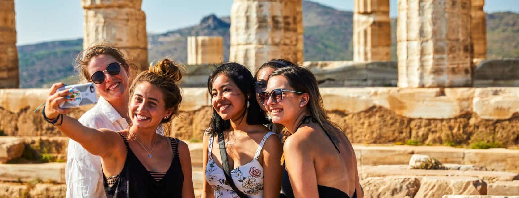Atlantis students posing for a photo by a Greek historical landmark.