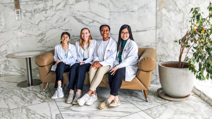 A group of students sitting on a bench ready to start shadowing in a hospital.