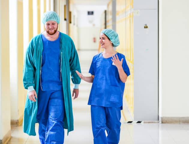 Students walking down the hallway in scrubs.