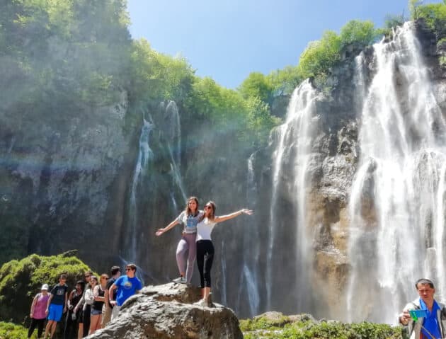 Students in front of a waterfall on a program excursion.