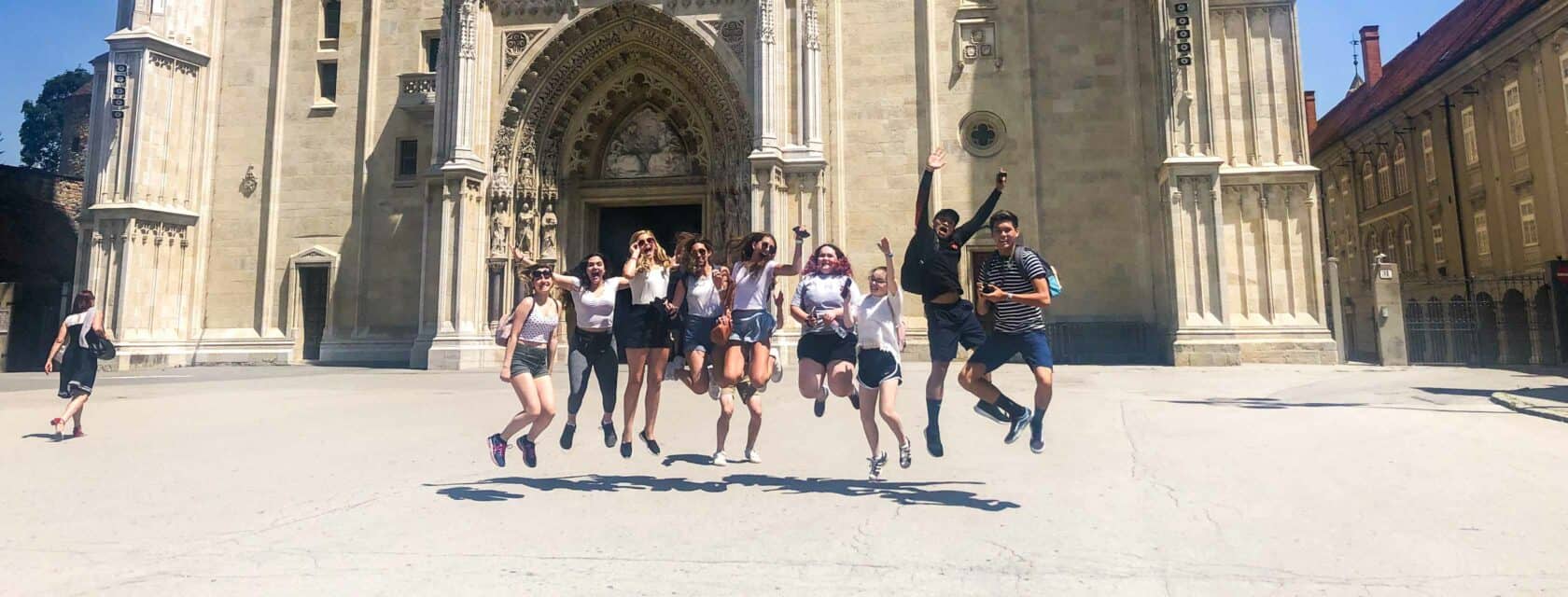 Students jumping in the air in front of a historical site.