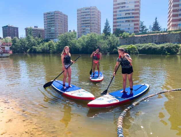 Students paddle boarding on the river beach.