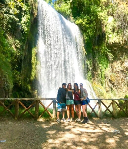 Students standing in front of a waterfall.