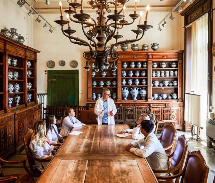 Students sitting around a table listening to a doctor.